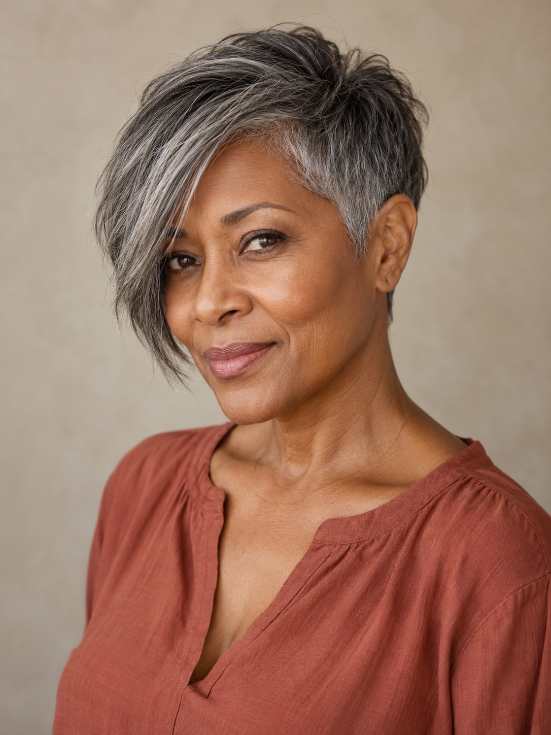 Older woman with a charcoal-and-silver asymmetric pixie, one short side and a long sweeping fringe